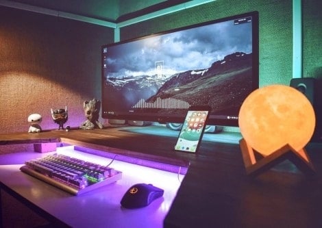 A gaming PC and a phone are on the table in the dark room