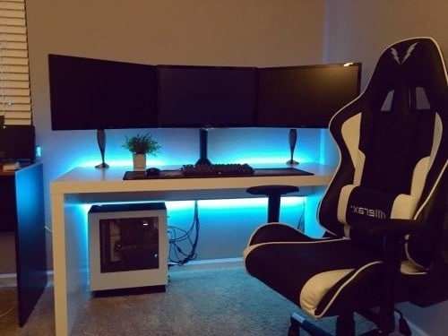 A huge monitor on the table and a black and white gaming chair