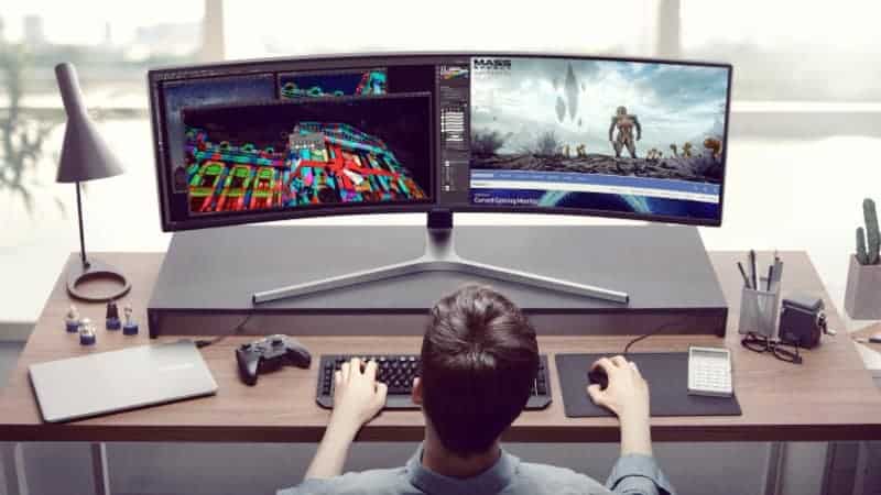 A young guy is playing on the two-screen computer
